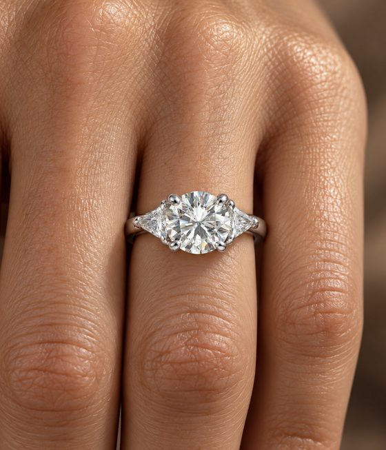 Round brilliant diamond flanked by two trillion-cut side stones on a polished band.