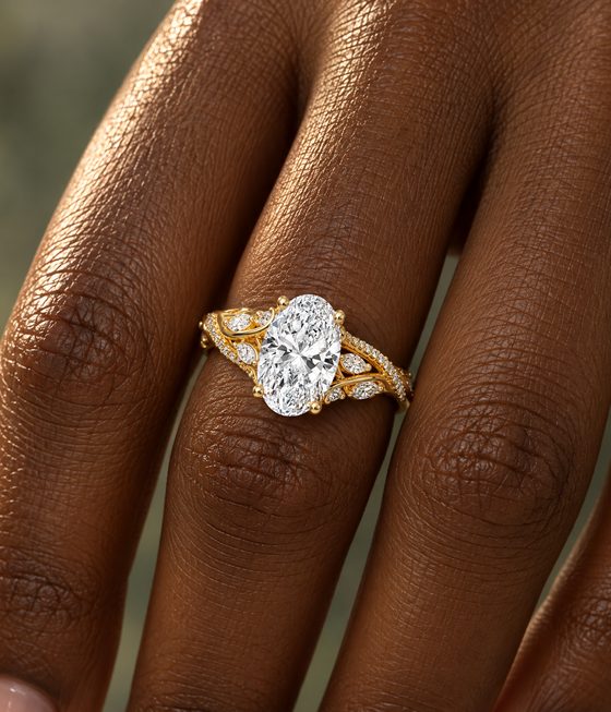 Oval diamond on a yellow gold split band of leaf-shaped marquise accents and small pavé diamonds.