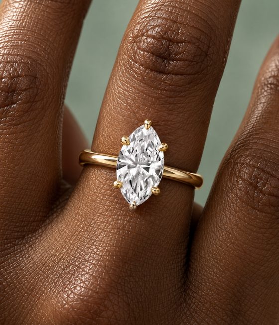 Marquise diamond held in six claw prongs on a plain yellow gold band.