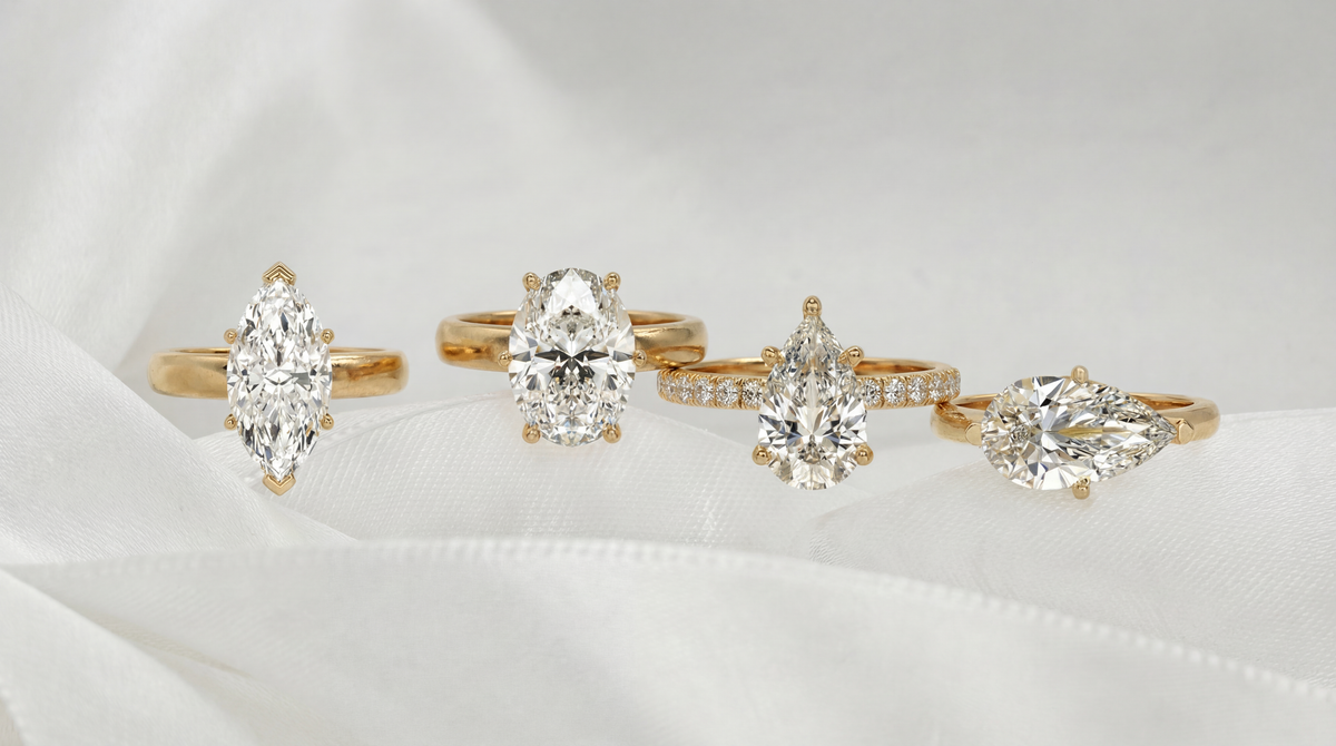 Four yellow gold engagement rings with marquise, oval, pear and sideways-set pear diamonds on white silk