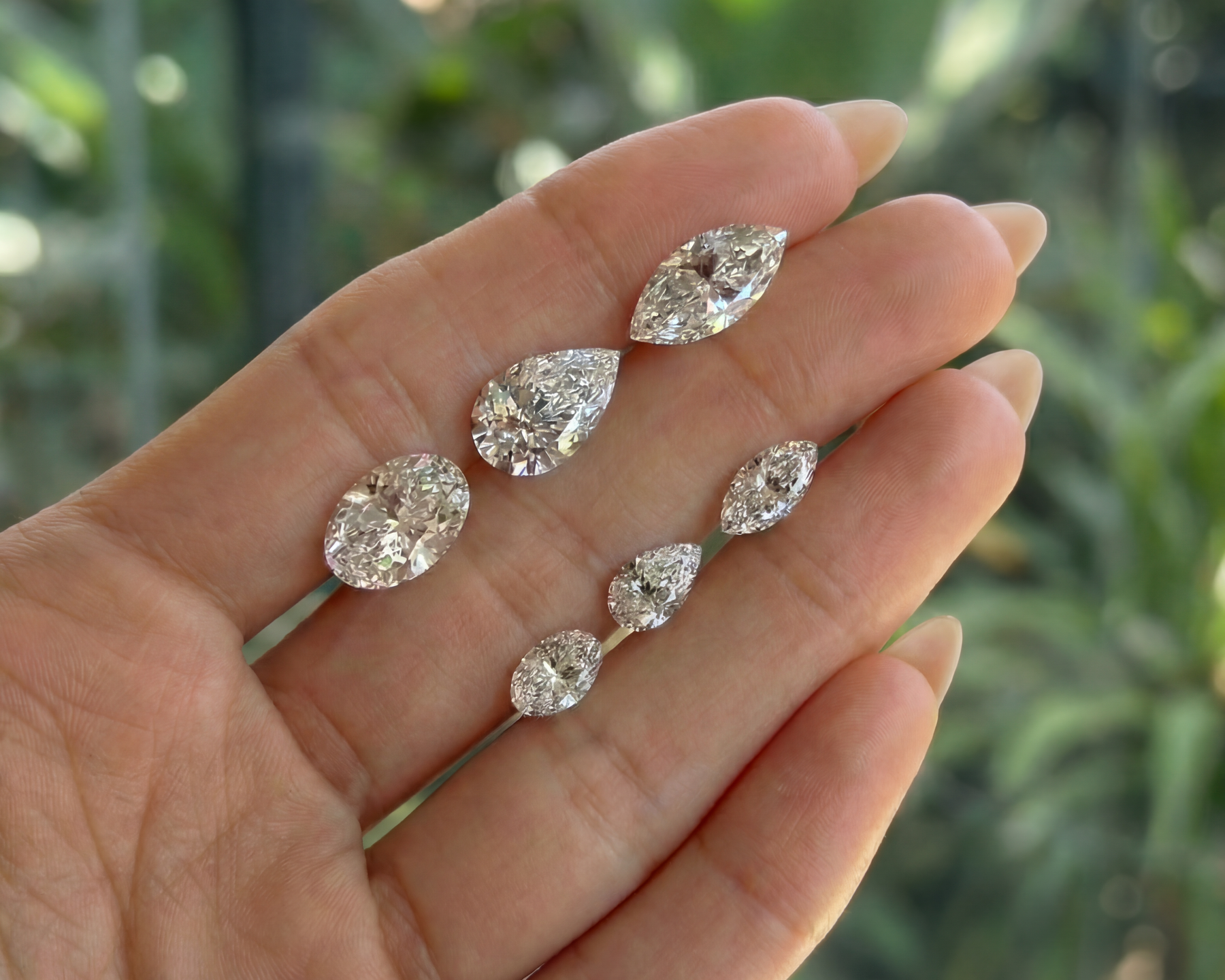 Loose pear, oval and marquise diamonds held in the palm of a hand