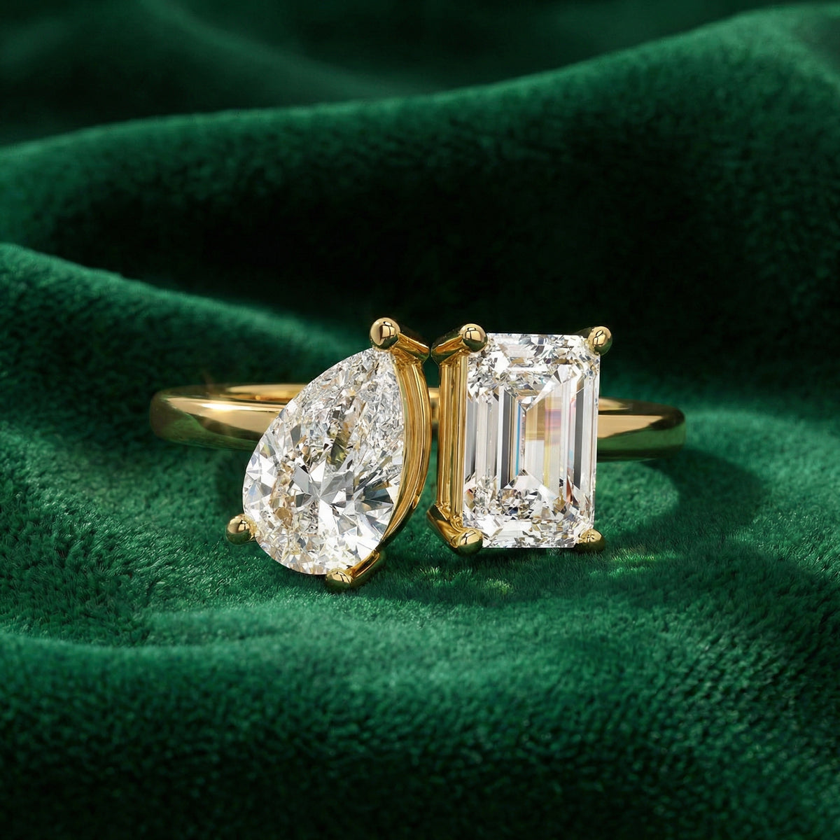 Vega pear and emerald toi-et-moi engagement ring in yellow gold on green velvet