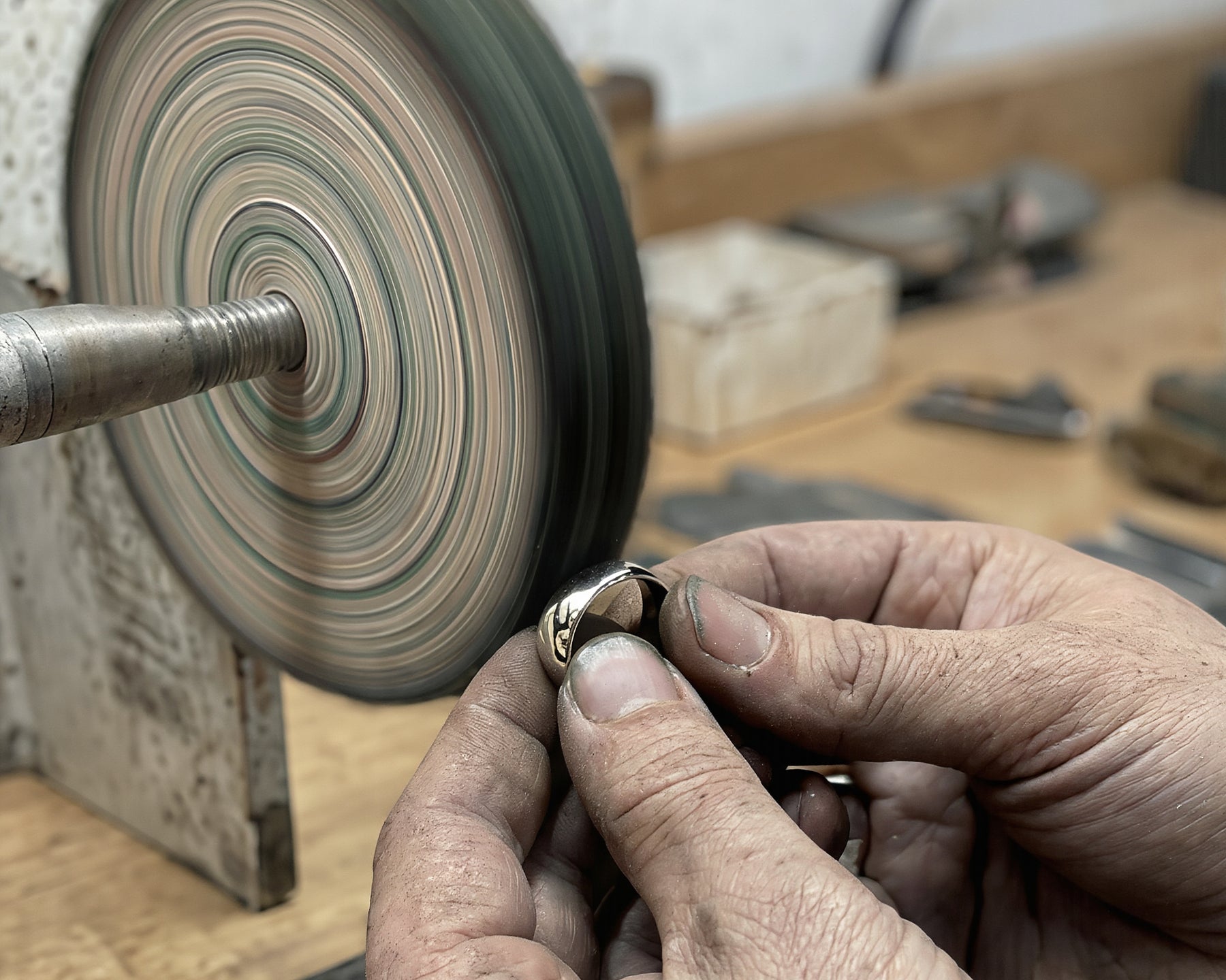 A jeweler's hands finishing a ring at a polishing wheel