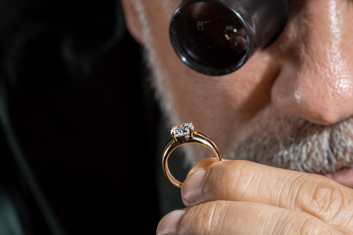 A jeweler examining a diamond engagement ring through an eye loupe