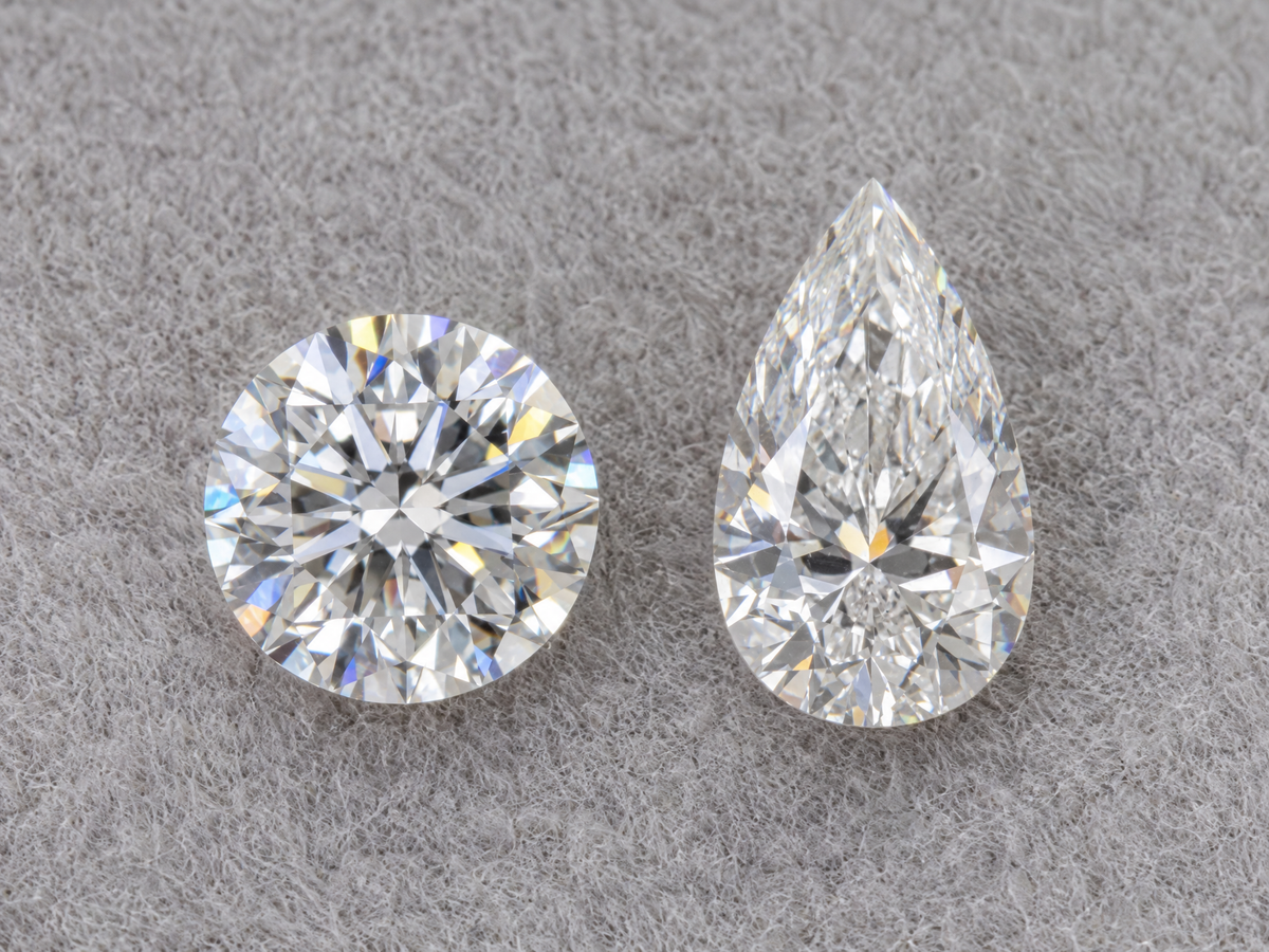 A round diamond and a pear shaped diamond of the same carat weight side by side, face up