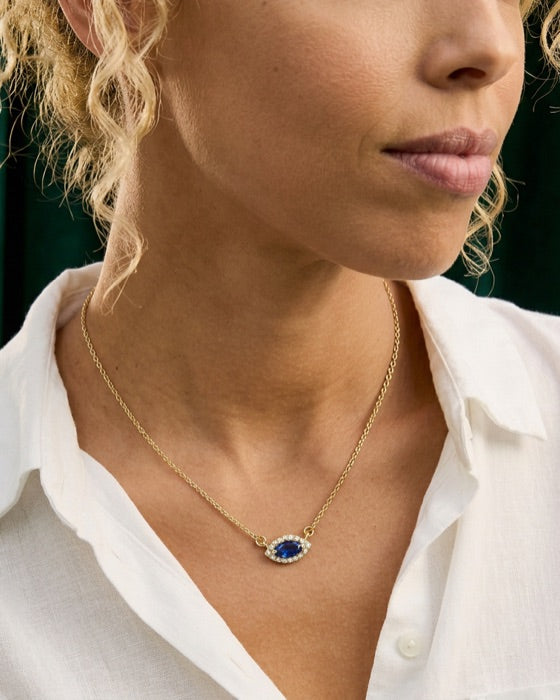 The neckline of a white linen shirt with a marquise blue sapphire and diamond pendant on a fine gold chain.